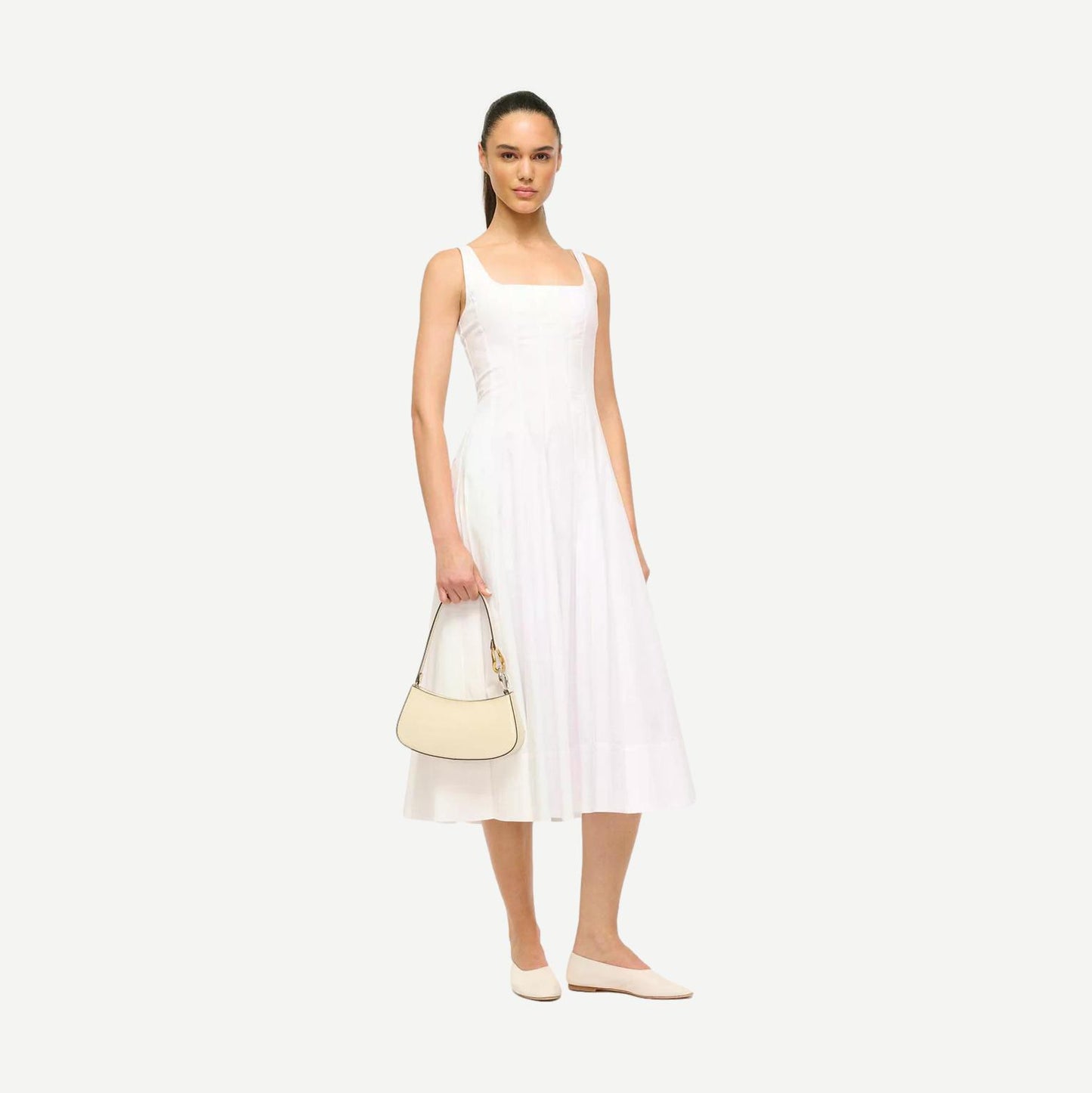 Cream Staud Ollie Bag purse with rounded shape and top handle, featuring a smooth leather finish and minimalist design.