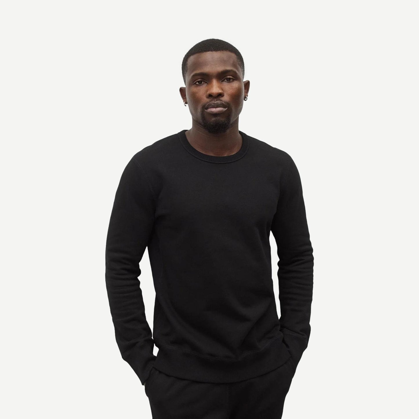 Black Reigning Champ midweight terry slim crewneck sweatshirt displayed on a hanger with a close-up view of fabric texture.