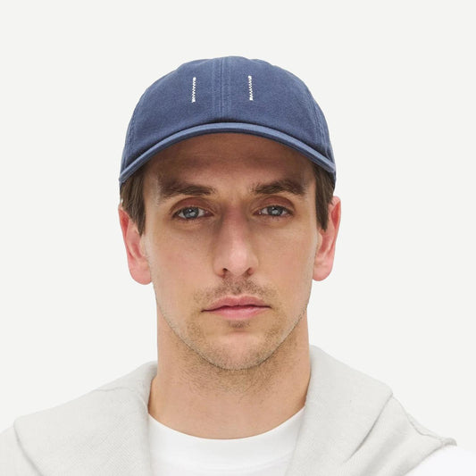 Reigning Champ cotton chino low pro strapback cap in washed navy, showing front view with adjustable strap and curved brim.
