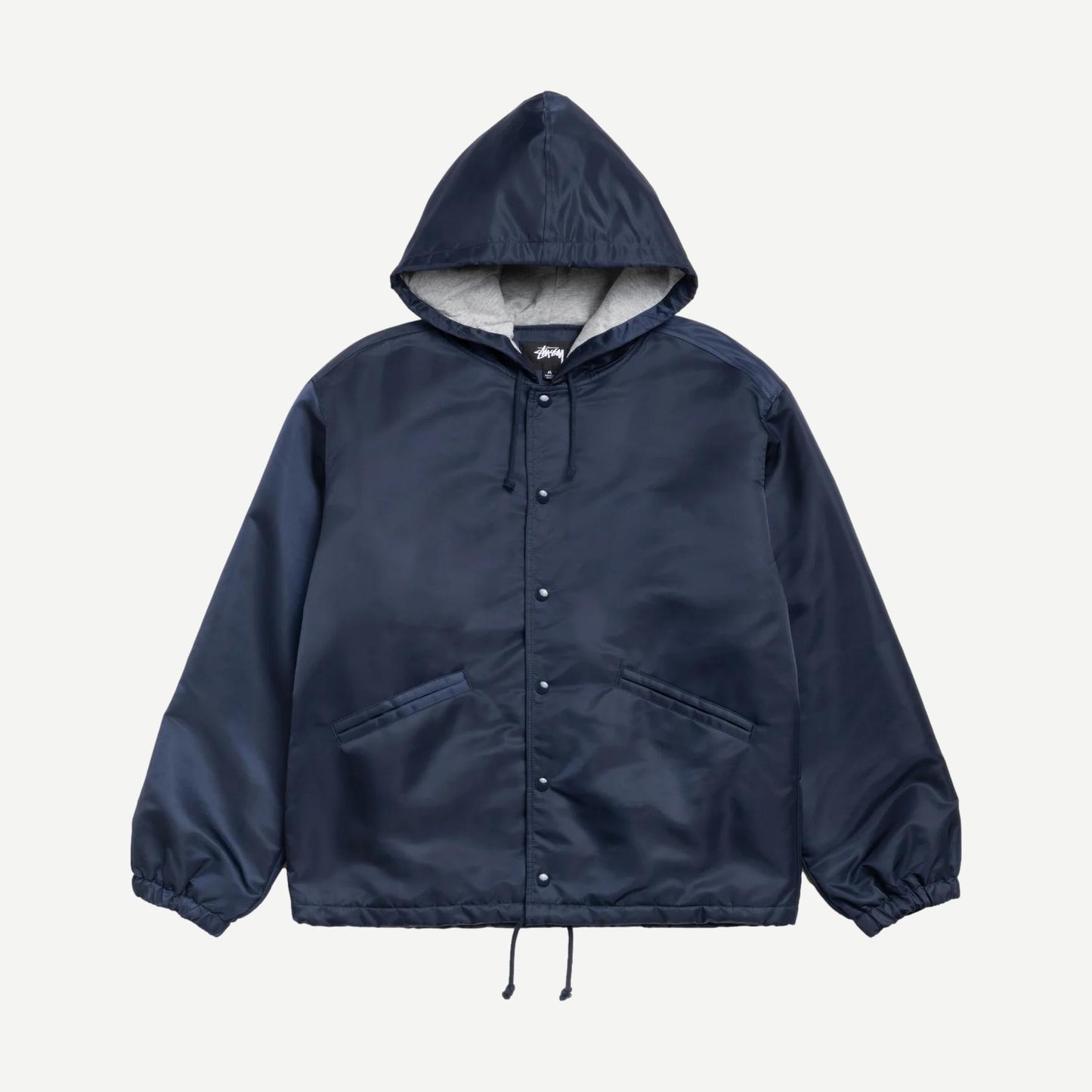 Navy Stussy hooded coaches jacket with front pockets and adjustable drawstrings, displayed on a hanger.