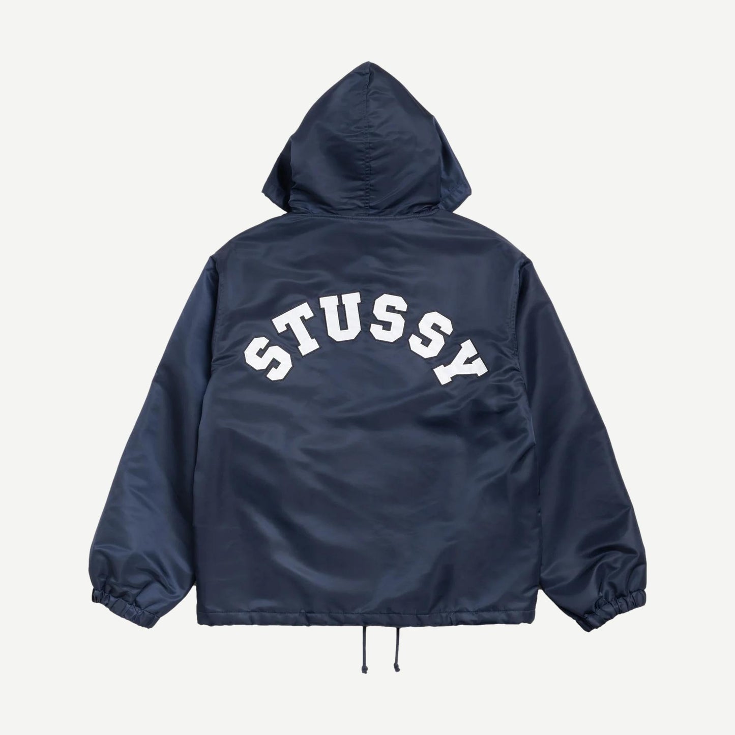 Navy hooded coaches jacket by Stussy, featuring a zip front, adjustable drawstring hood, and ribbed cuffs, displayed on a hanger.