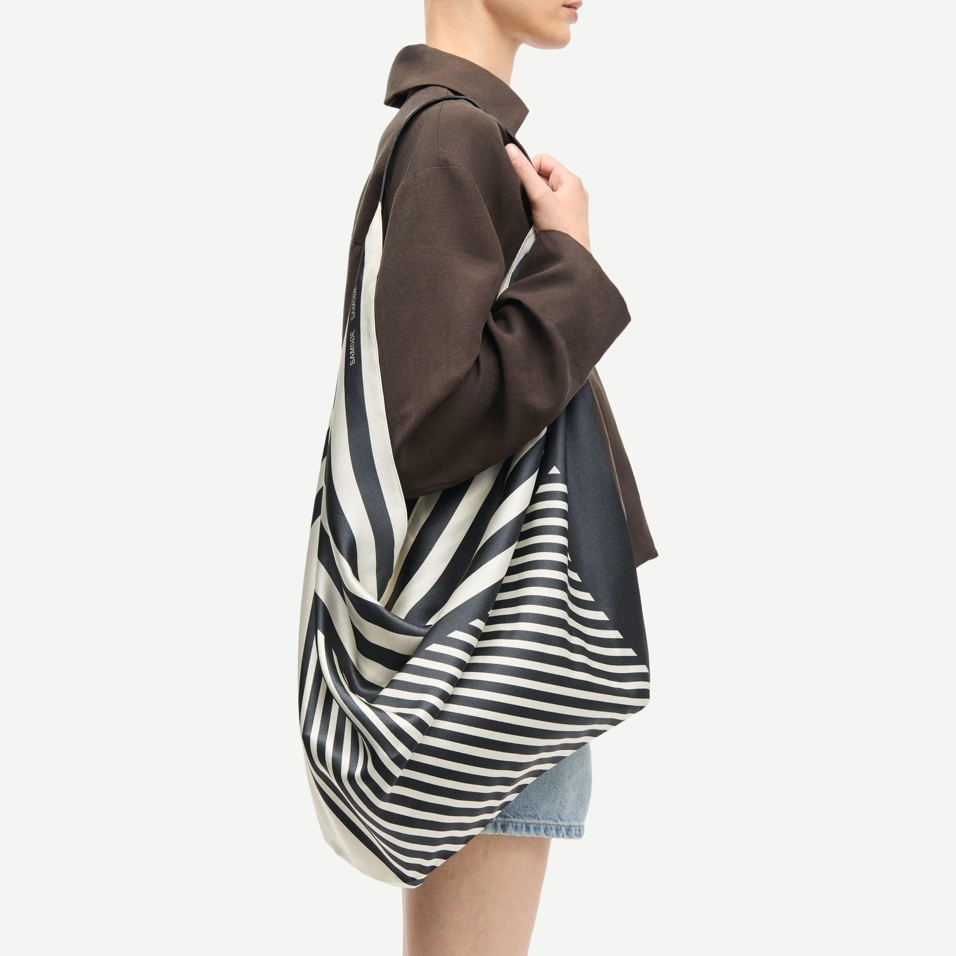 Black Saelli Scarf Bag by Samsoe Samsoe, stylish bag with scarf detail, shown in a close-up image.