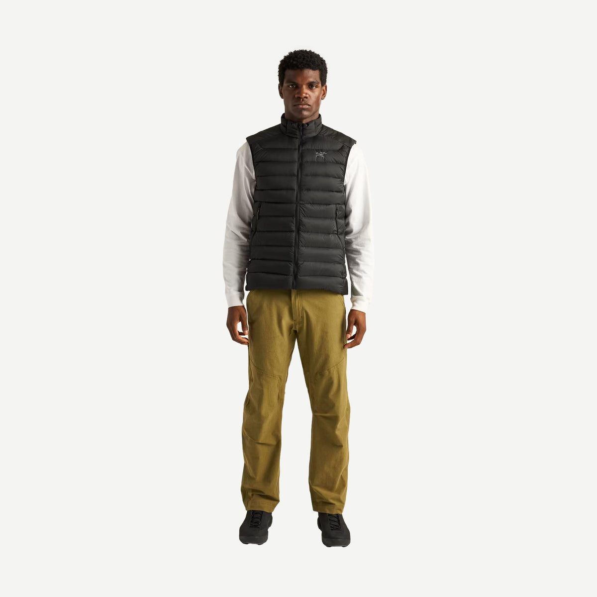 Black Arcteryx Cerium Vest men's outerwear, lightweight insulated vest with full zipper and high collar, shown on a model.
