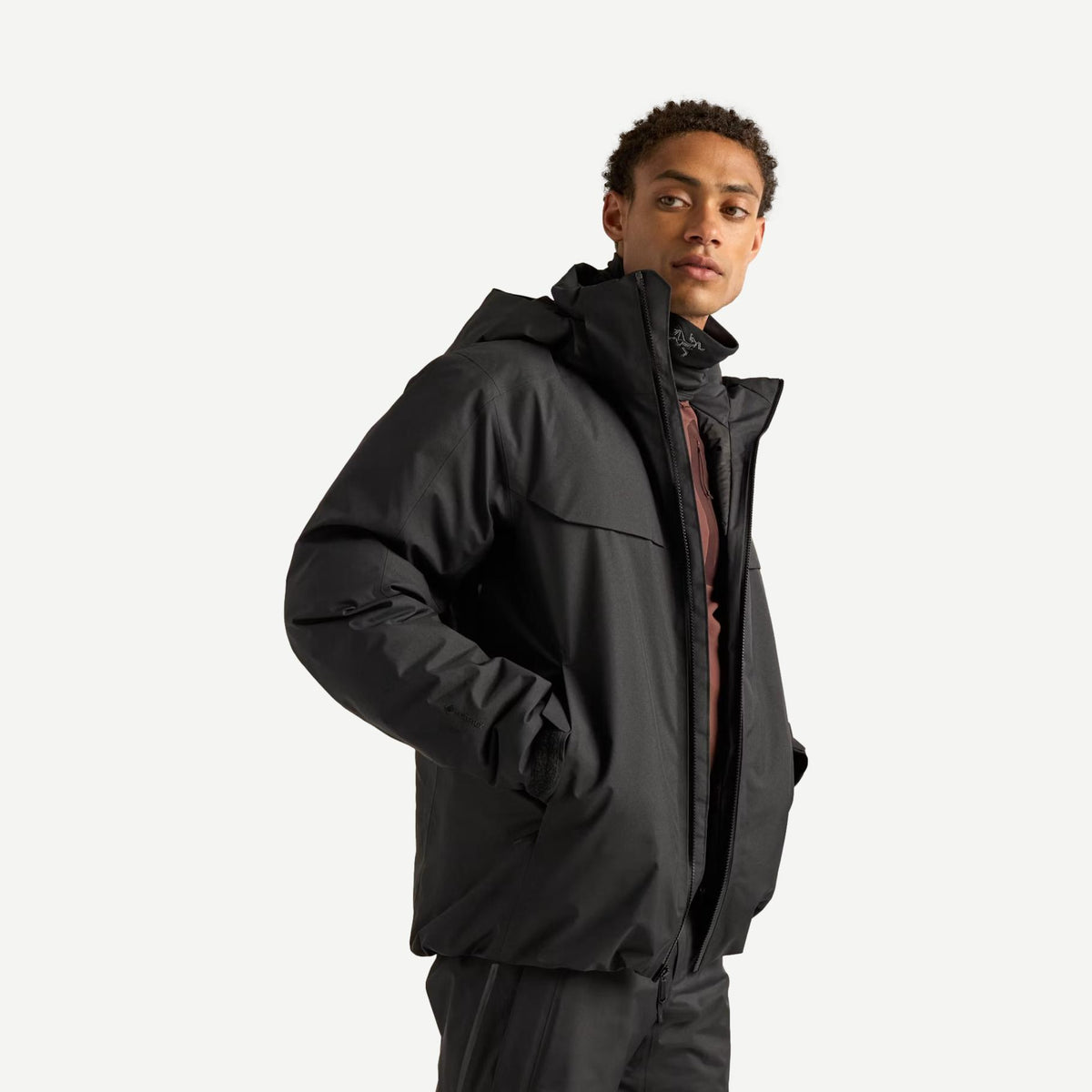 Men's black Arcteryx Macai down jacket showing close-up of the quilted outerwear with a high collar and sleek design.