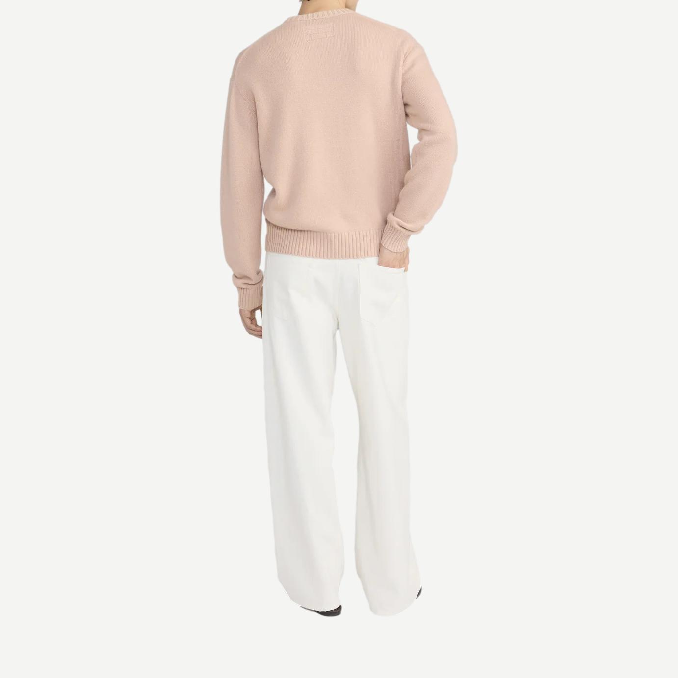Pale peach cashmere crewneck sweater by Frame Denim, featuring a classic fit and soft texture, laid flat on a surface.