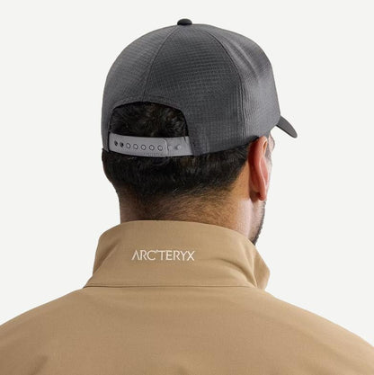 Black and cloud-colored Arcteryx Bird Word Trucker Hat shown from the back view, featuring a mesh trucker style and embroidered logo.