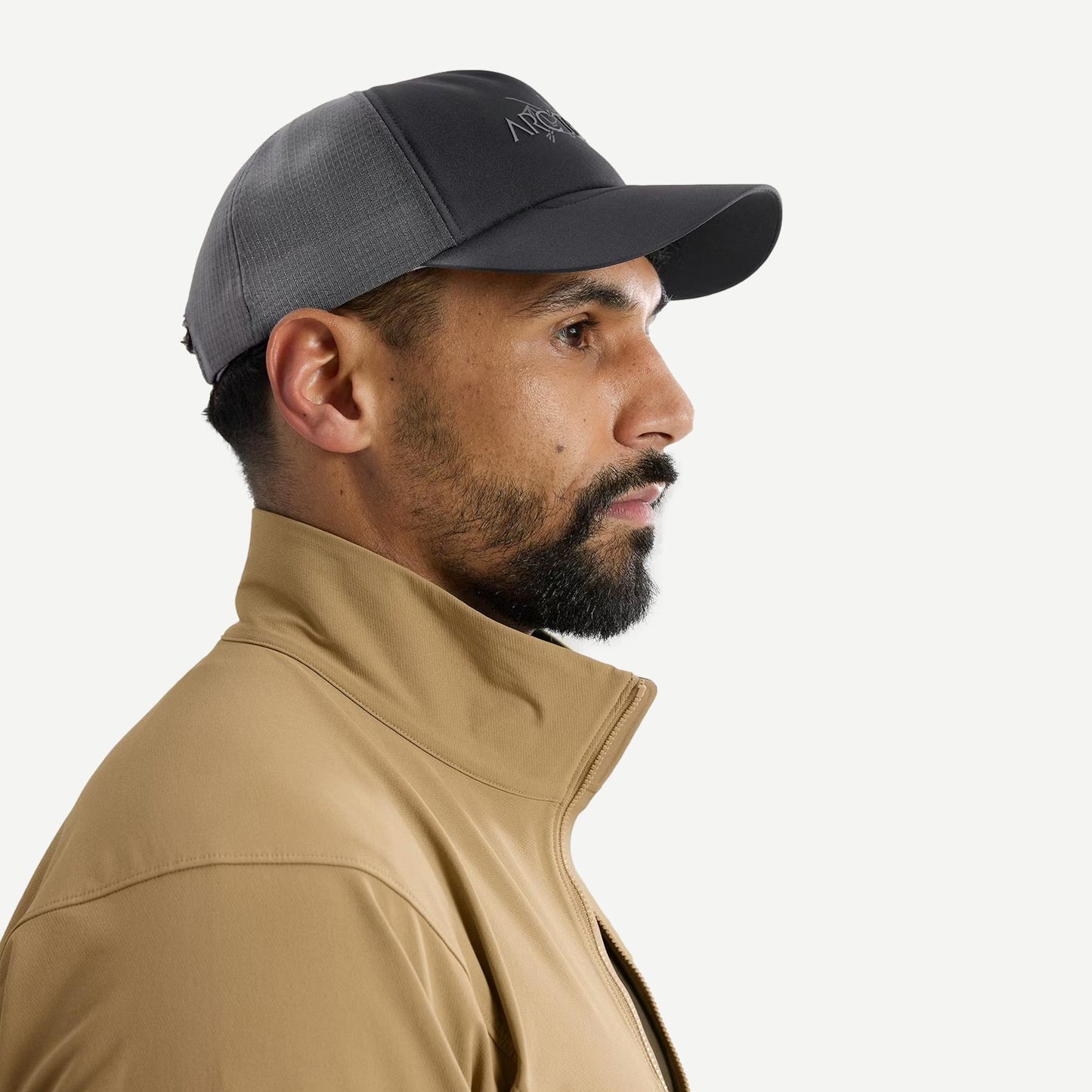 Black and cloud-colored Arcteryx Bird Word Trucker Hat with mesh side view, casual outdoor style, adjustable brim, and embroidered logo.