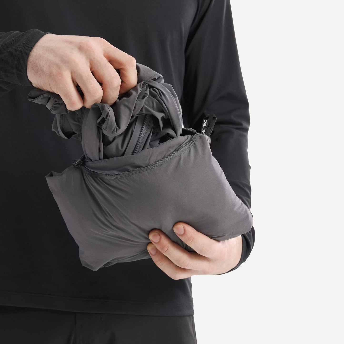 Arcteryx Atom SL Hoody M in Cloud, a lightweight jacket with a sleek design, shown packed and clipped for outdoor use.