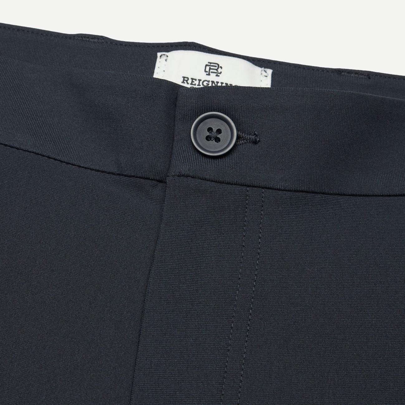 Reigning Champ navy stretch warp knit coach's slim pants displayed on a model, showing front view with relaxed fit and subtle branding.