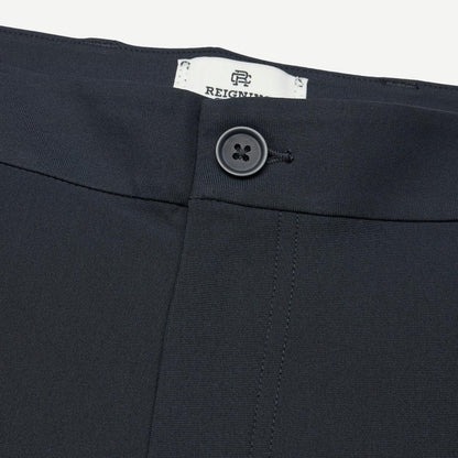Reigning Champ navy stretch warp knit coach's slim pants displayed on a model, showing front view with relaxed fit and subtle branding.