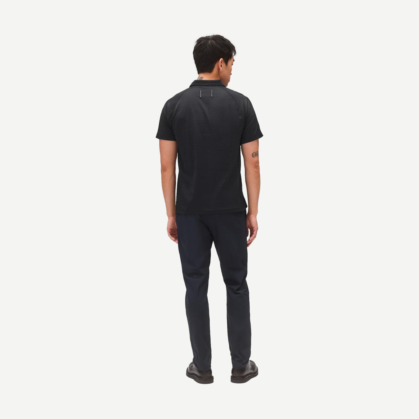 Reigning Champ navy stretch warp knit coach's slim pants displayed on a model, showing a sleek, fitted style with a tapered leg.