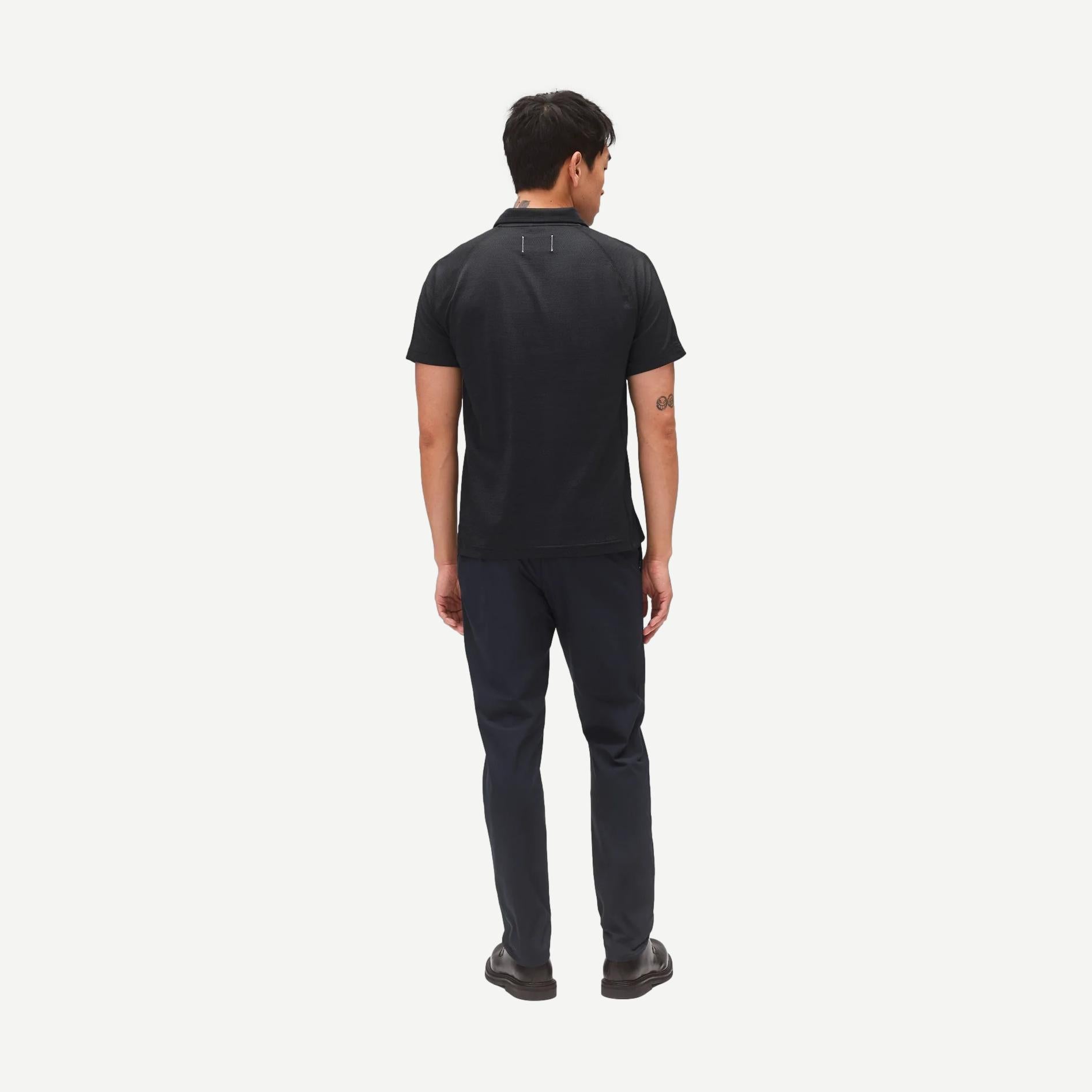 Reigning Champ navy stretch warp knit coach's slim pants displayed on a model, showing a sleek, fitted style with a tapered leg.