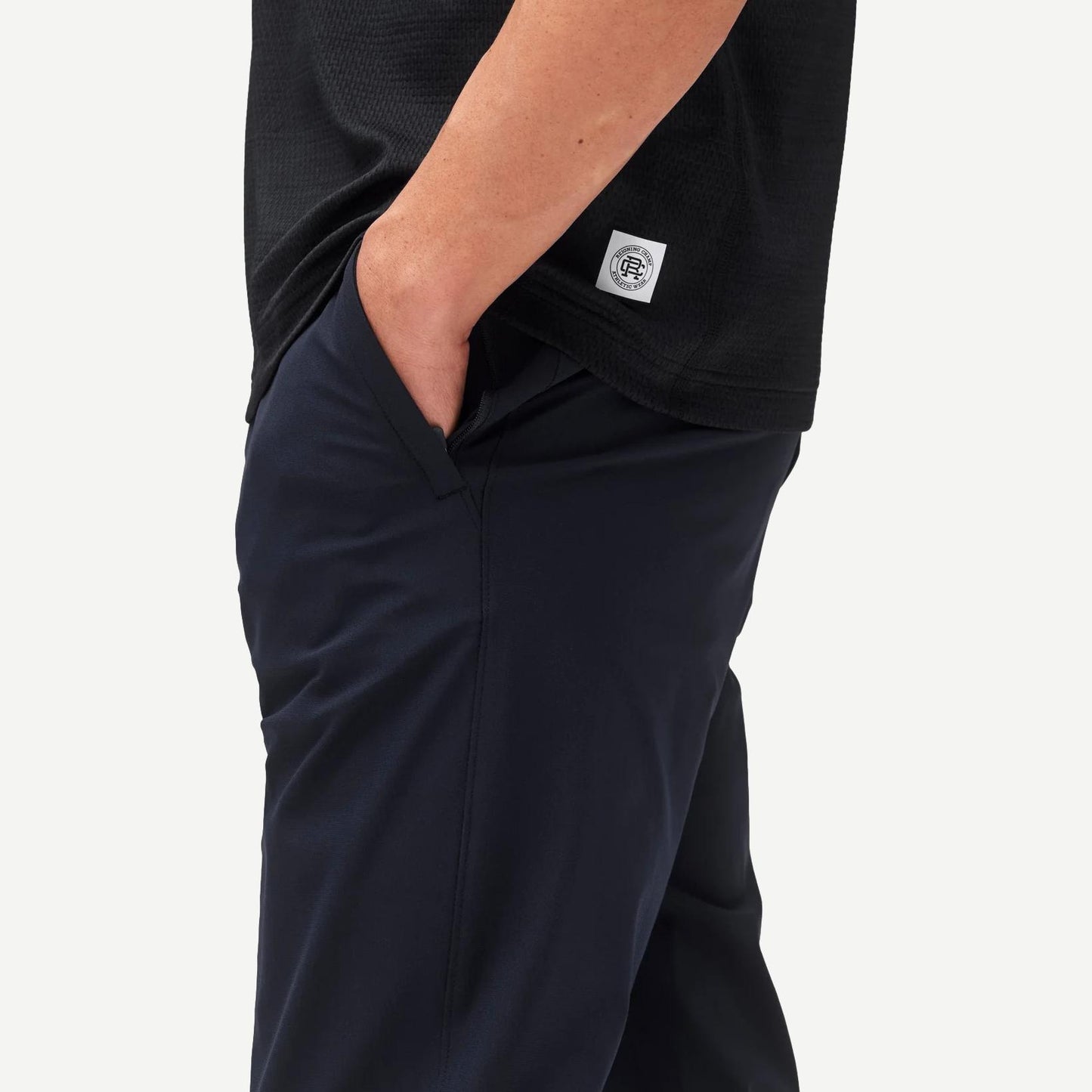 Reigning Champ navy stretch warp knit coach's slim pants displayed on a model with a relaxed fit and modern design.