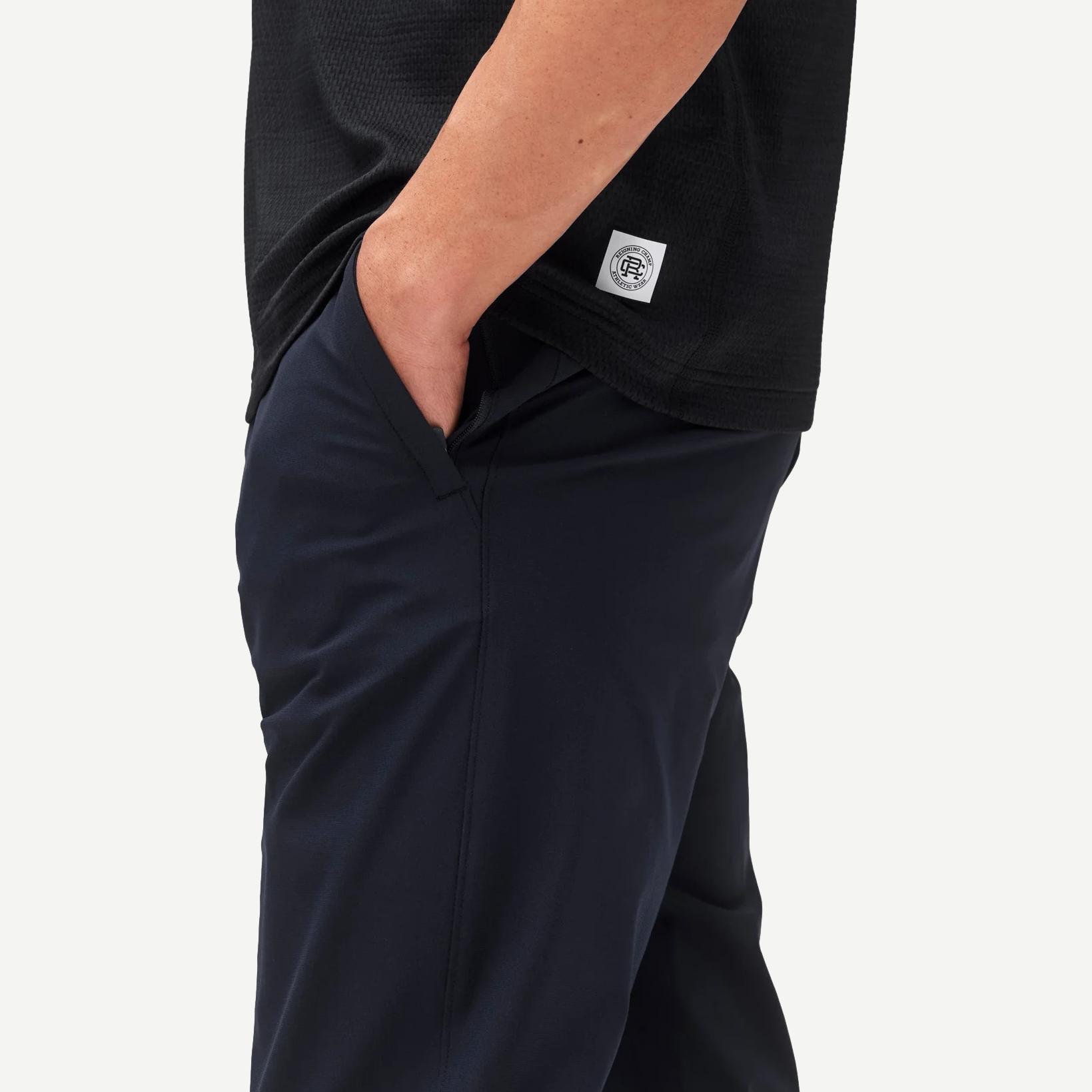 Reigning Champ navy stretch warp knit coach's slim pants displayed on a model with a relaxed fit and modern design.