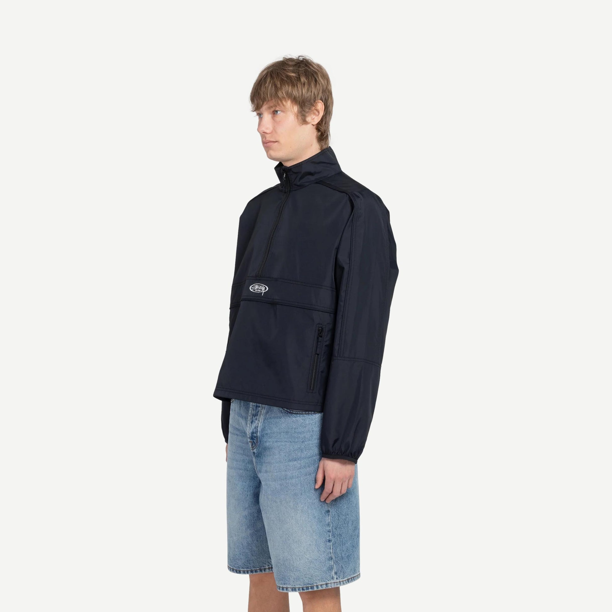 Black lightweight pullover jacket by Stussy, shown on a model with a relaxed fit and minimal design.