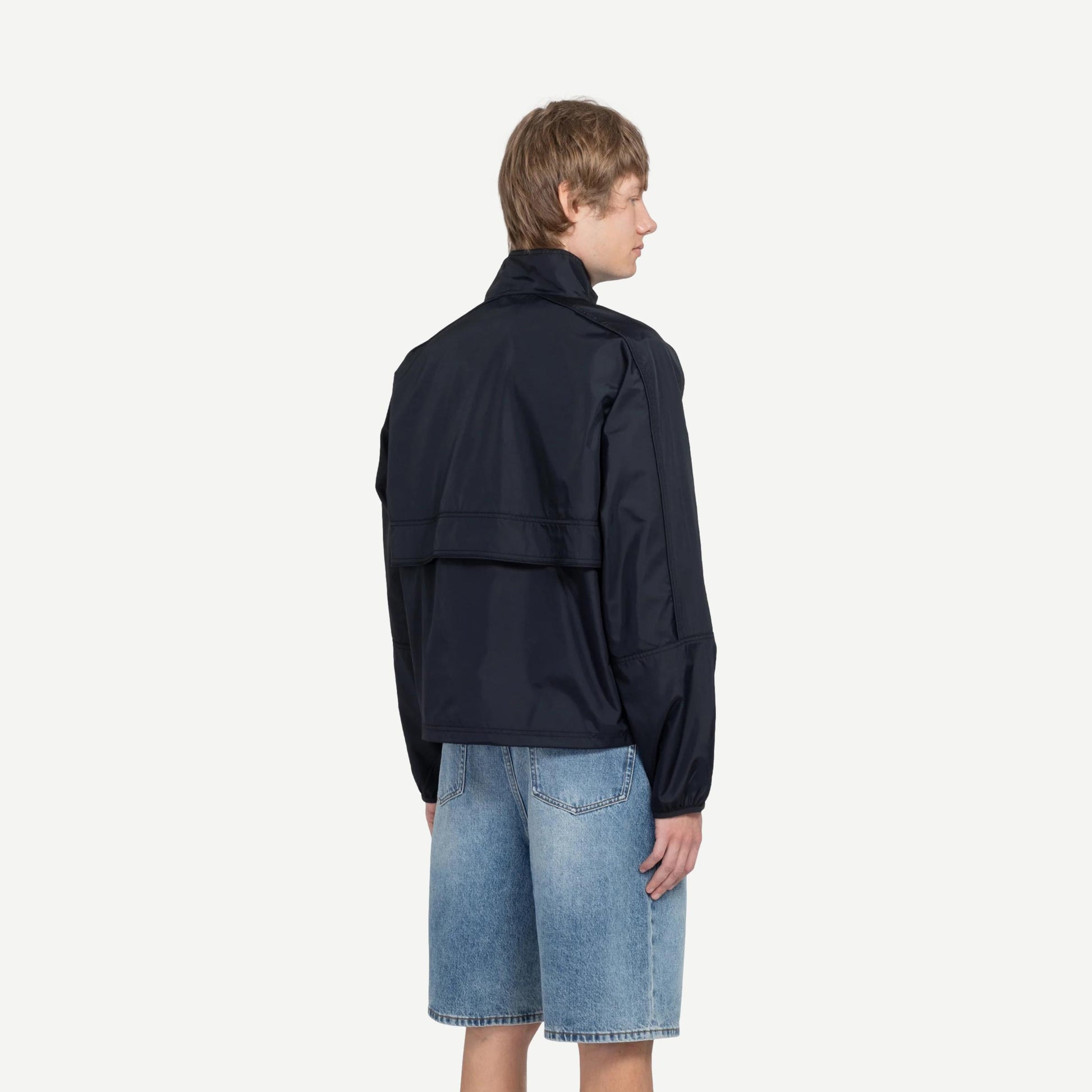 Black Stussy lightweight pullover jacket, casual fit with subtle branding, shown on a hanger against a plain background.