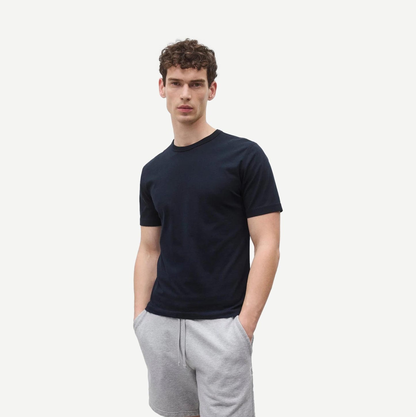 Reigning Champ navy lightweight jersey slim T-shirt displayed on a hanger with a close-up of fabric texture.