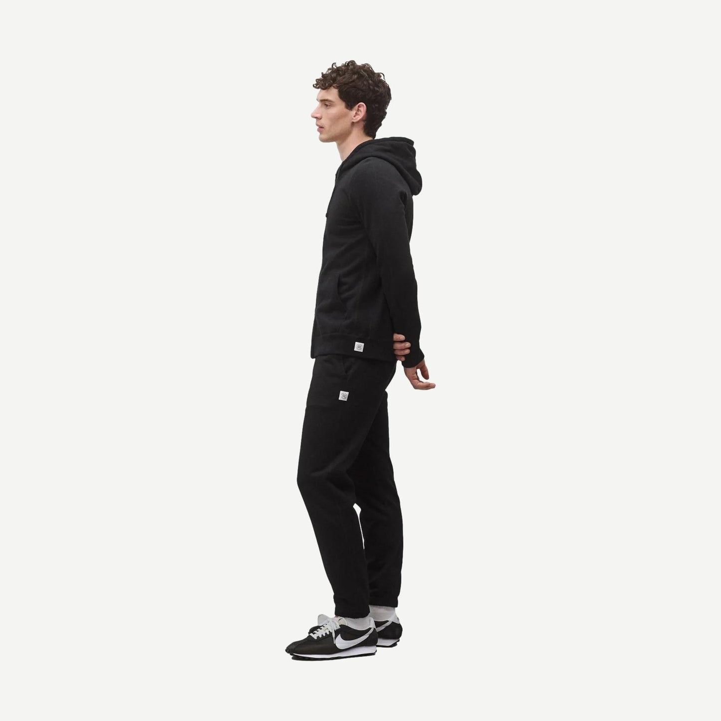 Black Reigning Champ midweight terry slim zip hoodie with front pockets and a stand-up collar, displayed on a hanger.