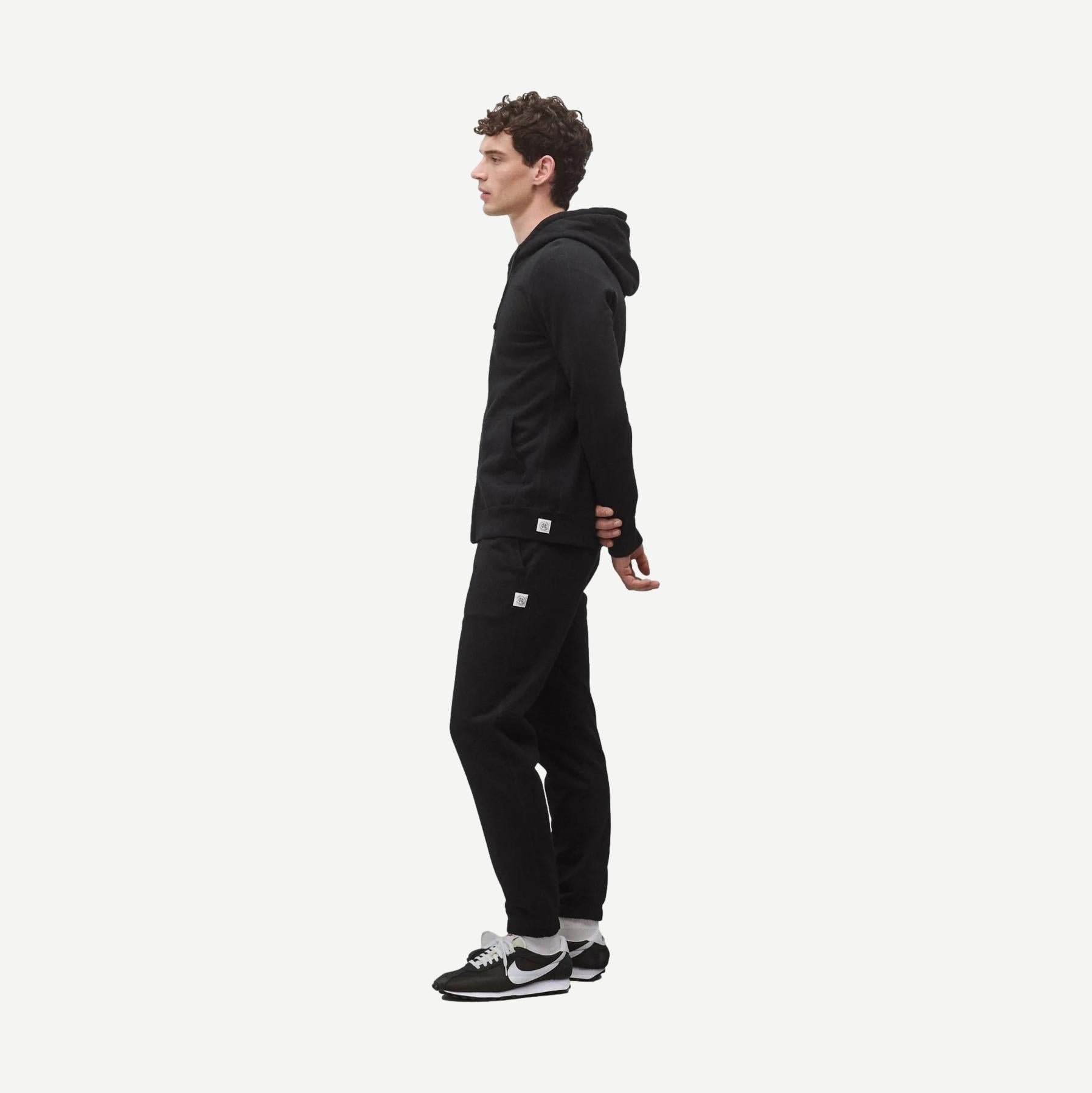 Black Reigning Champ midweight terry slim zip hoodie with front pockets and a stand-up collar, displayed on a hanger.