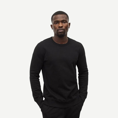 Black Reigning Champ midweight terry slim crewneck sweatshirt displayed on a hanger with a close-up view of fabric texture.