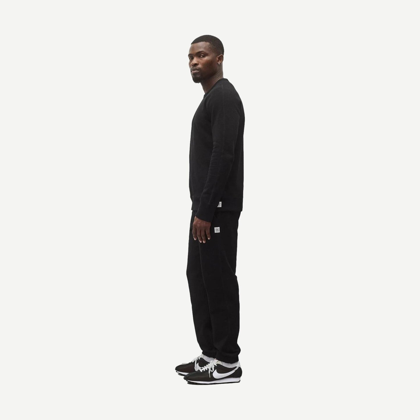 Reigning Champ black midweight terry slim crewneck sweatshirt displayed on a hanger, showcasing its soft fabric and classic fit.