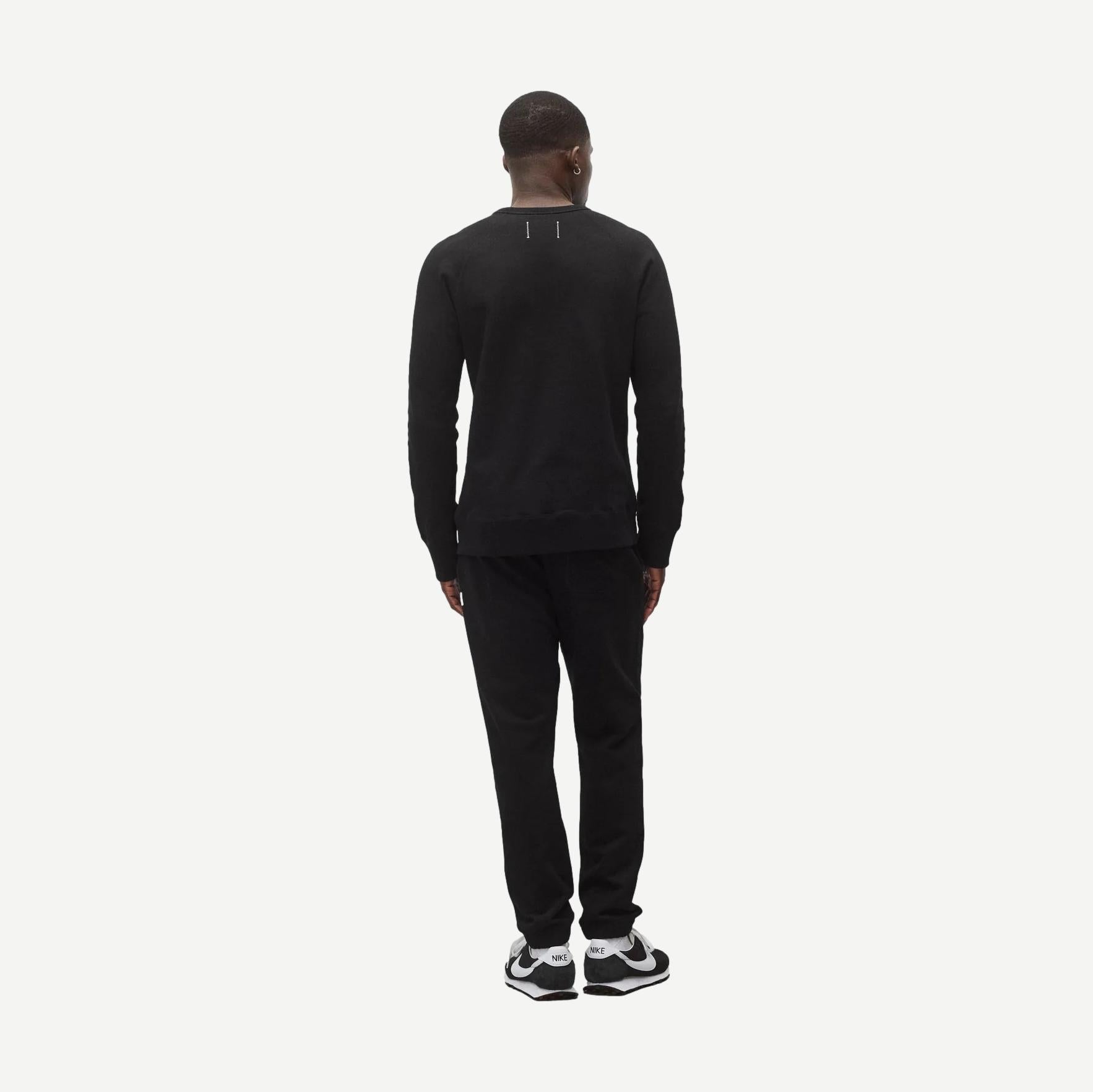 Reigning Champ black midweight terry slim crewneck sweatshirt displayed on a model, showcasing a classic fit and soft fabric.