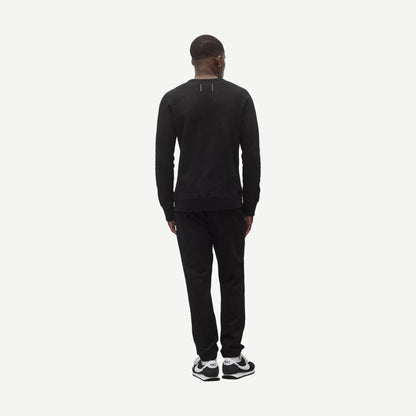 Reigning Champ black midweight terry slim crewneck sweatshirt displayed on a model, showcasing a classic fit and soft fabric.
