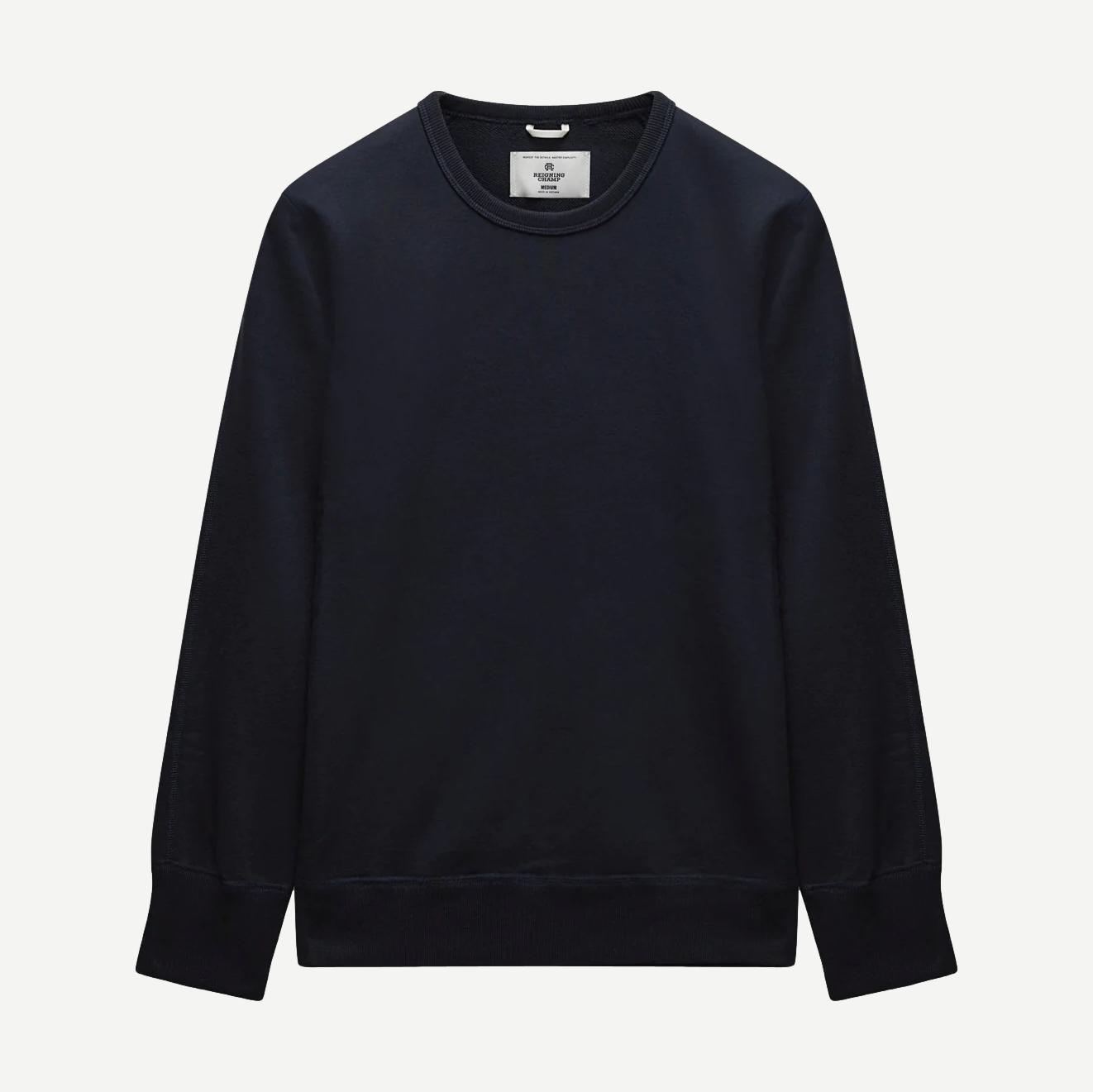 Reigning Champ navy midweight terry slim crewneck sweatshirt displayed on a hanger, showcasing its soft fabric and classic fit.