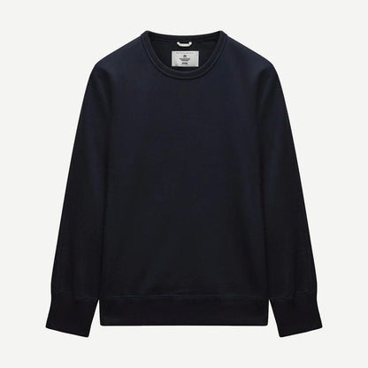 Reigning Champ navy midweight terry slim crewneck sweatshirt displayed on a hanger, showcasing its soft fabric and classic fit.
