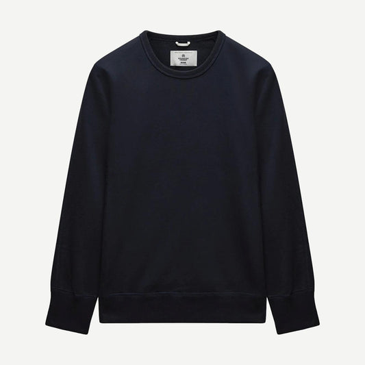 Reigning Champ navy midweight terry slim crewneck sweatshirt displayed on a hanger, showcasing its soft fabric and minimalist design.