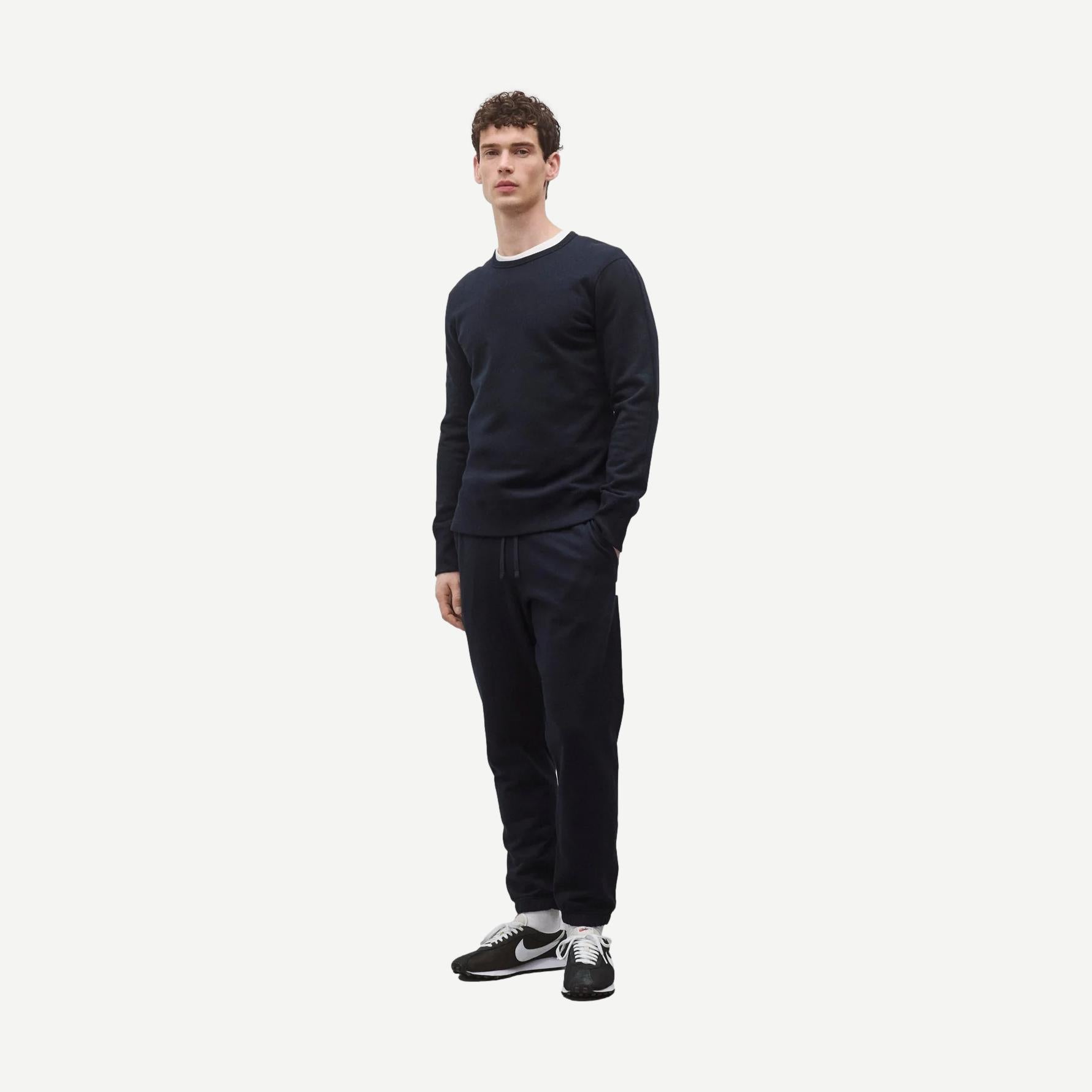 Navy midweight Terry slim crewneck sweatshirt by Reigning Champ displayed on a hanger with a close-up view of fabric and stitching.