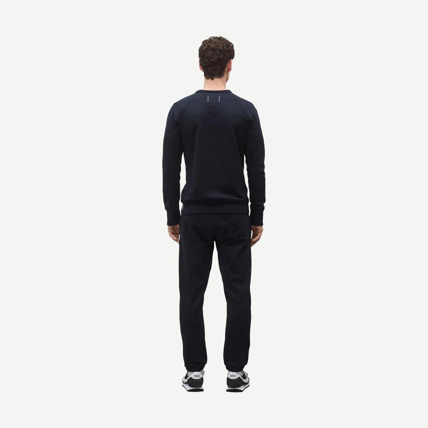 Reigning Champ navy midweight terry slim crewneck sweatshirt displayed on a model, showcasing a casual, comfortable fit.
