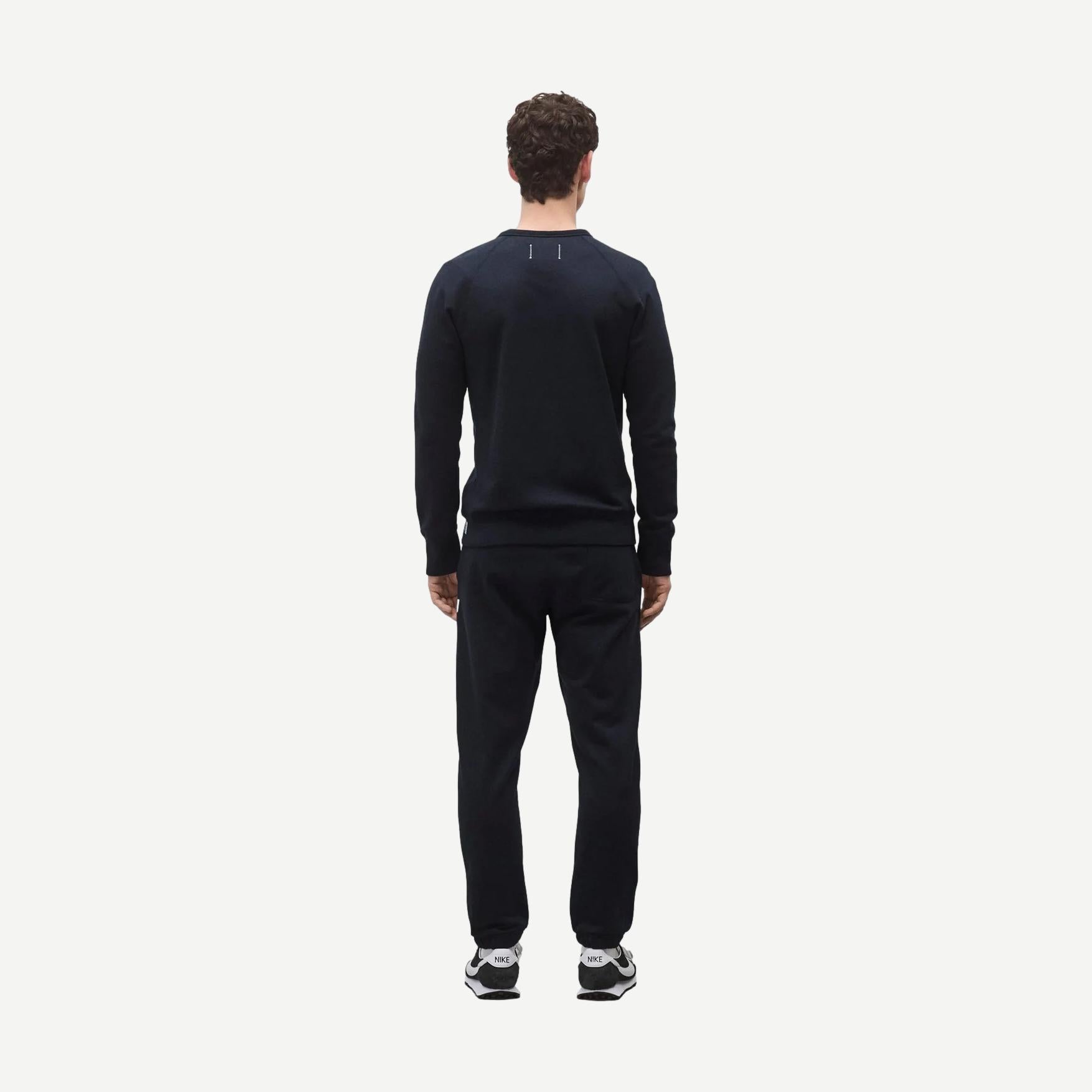 Reigning Champ navy midweight terry slim crewneck sweatshirt displayed on a model, showcasing a casual, comfortable fit.