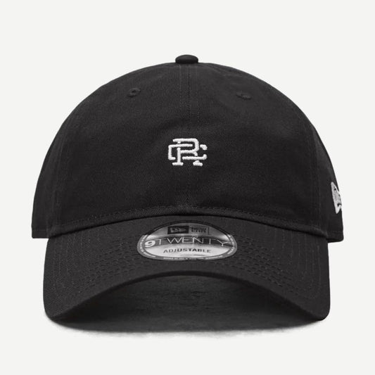 Reigning Champ New Era 9Twenty mini monogram black cap with curved brim and adjustable strap, shown from front view.