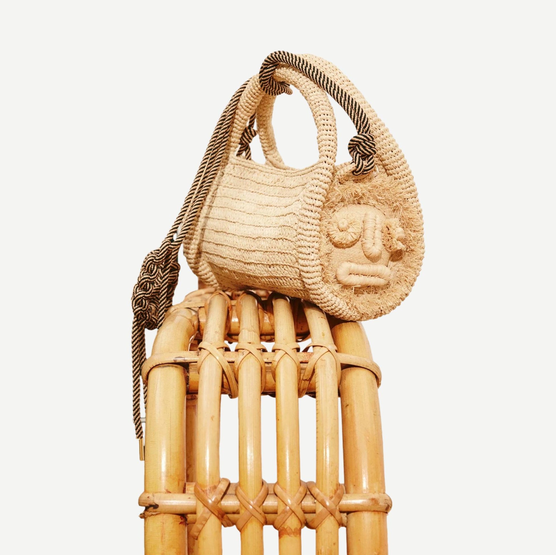 Alémais Sunlit Raffia Mini Barrel Bag in blonde with woven texture, small purse with rounded shape and top handle.