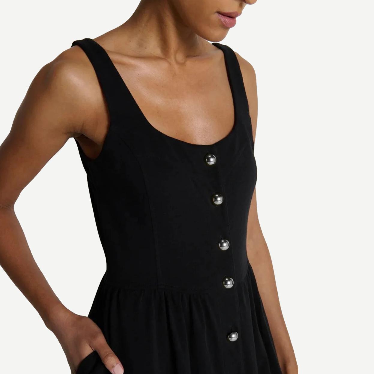 Jet black Nation LTD Laurel midi dress hanging on a clothing rack with a simple, elegant design and sleeveless style.